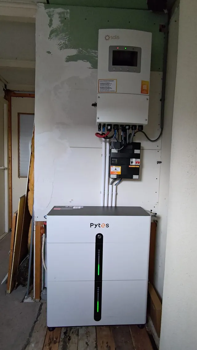Echte frontale opname van een compacte thuisbatterij en omvormer in een smalle ruimte