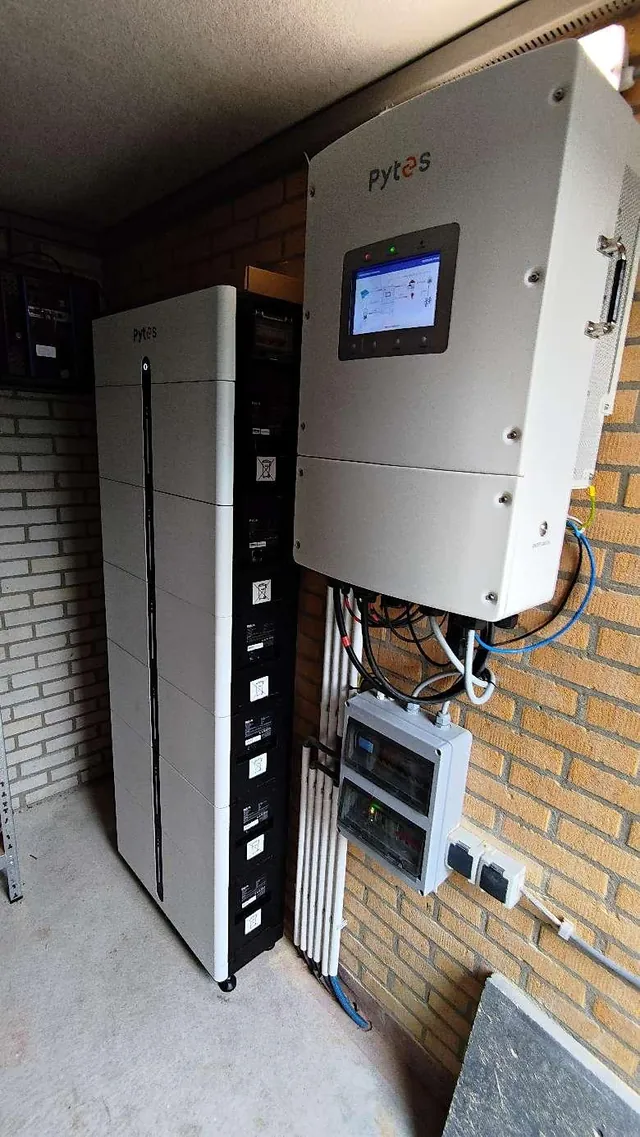 Echte detailopname van een hoge batterijopstelling met omvormer tegen een bakstenen wand